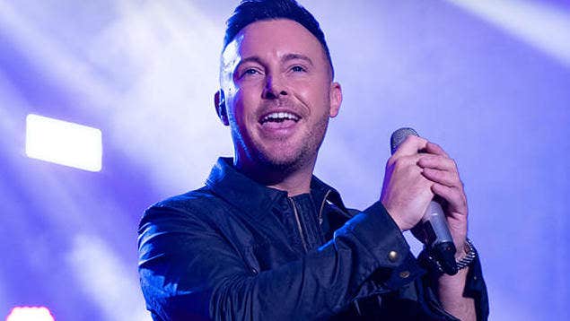 A man is singing, holding a mic in both hands