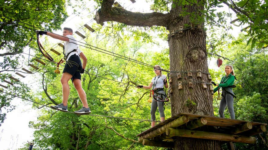 Two people ziplining through the trees with the guidance of an instructor at Lough Key Zip Line