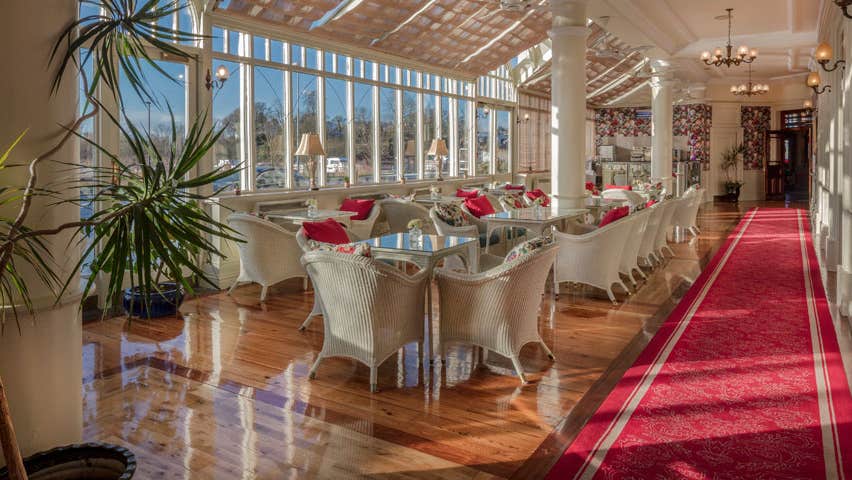 A row of tables and chairs along  a line of windows at the Aroma Café