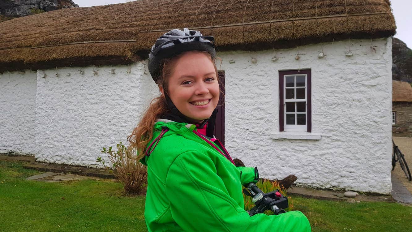 Lady stands with her electric bicycle at Glencolmcille Folk Village Experience with Ireland By Bike