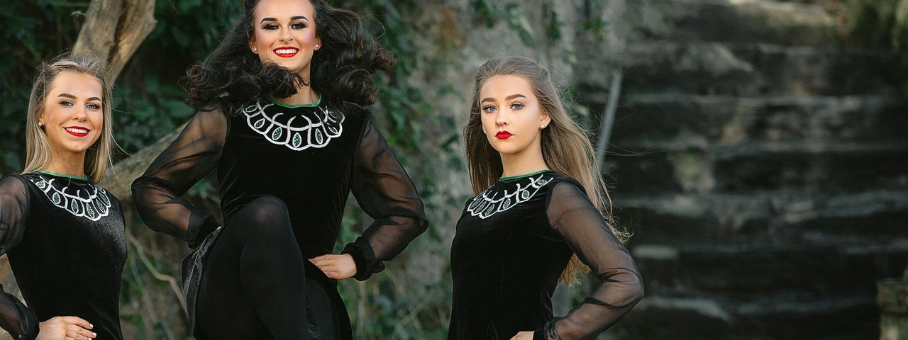 Three Irish dancers wearing Celtic dress performing with Twist of Irish