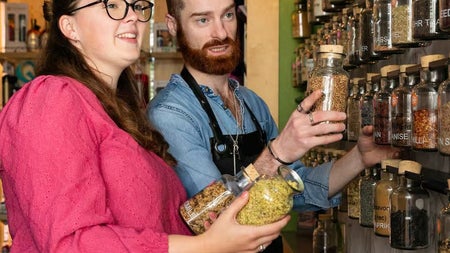 Two people looking at the jar of the botanicals for the gin