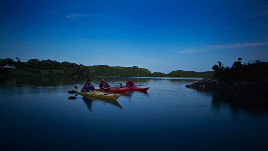 A group of people night kayaking on Lough Hyne in West Cork