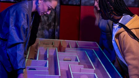 Three girls playing a maze puzzle