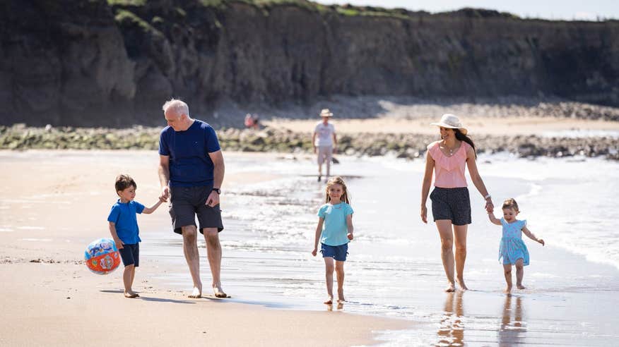 Family walking along the shore at Spanish Point in Clare