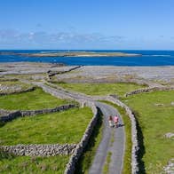 A road lined with stone walls leading to the sea