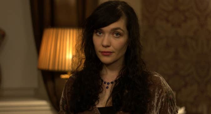 A woman sat beside a dimly lit orange lamp.