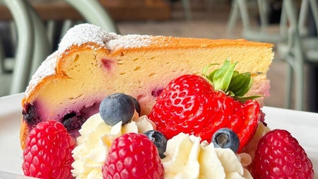 A thick slice of cake garnished with strawberries and cream