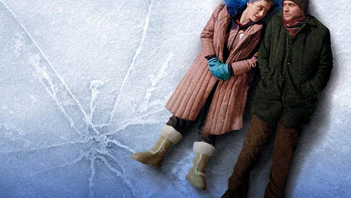 2 people dressed in winter coats are lying on their backs close together on icy surface.