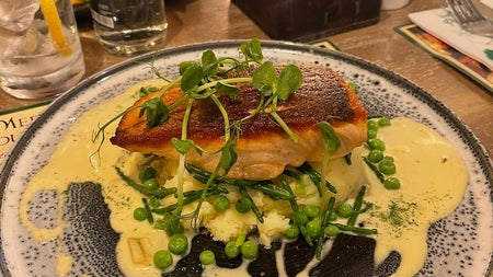 A fish dish with sauce on a white plate with a blue speckled pattern