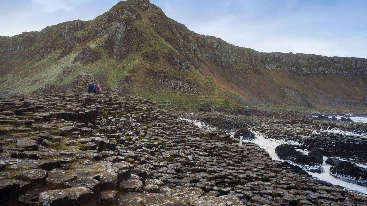 Giants causeway with people in the distance and a mountain in the background