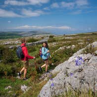 Two people with backbacks walking along a rocky landscape