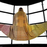 Person modelling a colourful scarf that is spread out over a bench