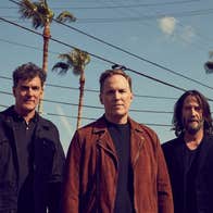 American alternative rock outfit Dogstar, 3 men outdoors with tall palm trees in the background.