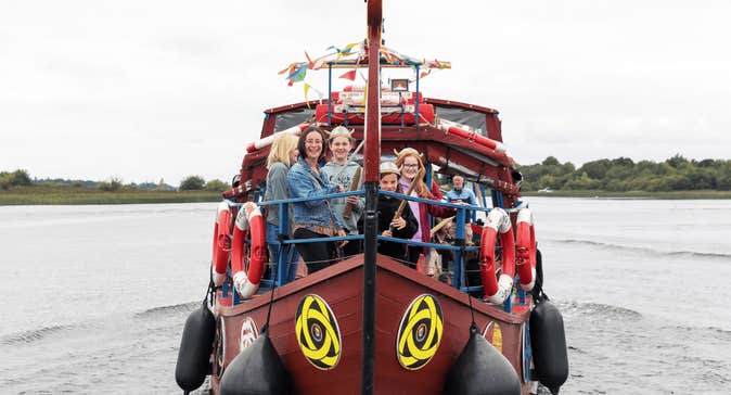 Viking Tours Cruise in Athlone, Co.Westmeath - small brown boat on a wide body of water with people standing around the front of boat.