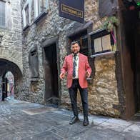 A tour guide in a pink jacket stands in a medieval laneway