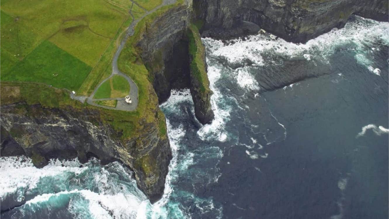 Helicopter view of the Cliffs of Moher with a glimpse of O Briens Tower