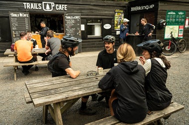 People with bicycle gear sitting on benches outside a café