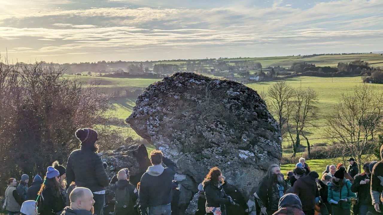 People standing around an ancient stone