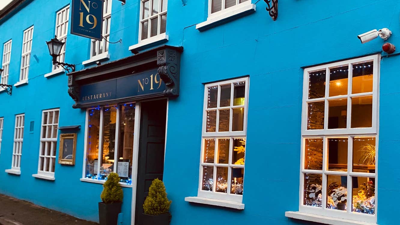 Exterior of a restaurant painted blue with a tavern style entrance painted a darker shade of blue