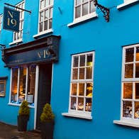 Exterior of a restaurant painted blue with a tavern style entrance painted a darker shade of blue