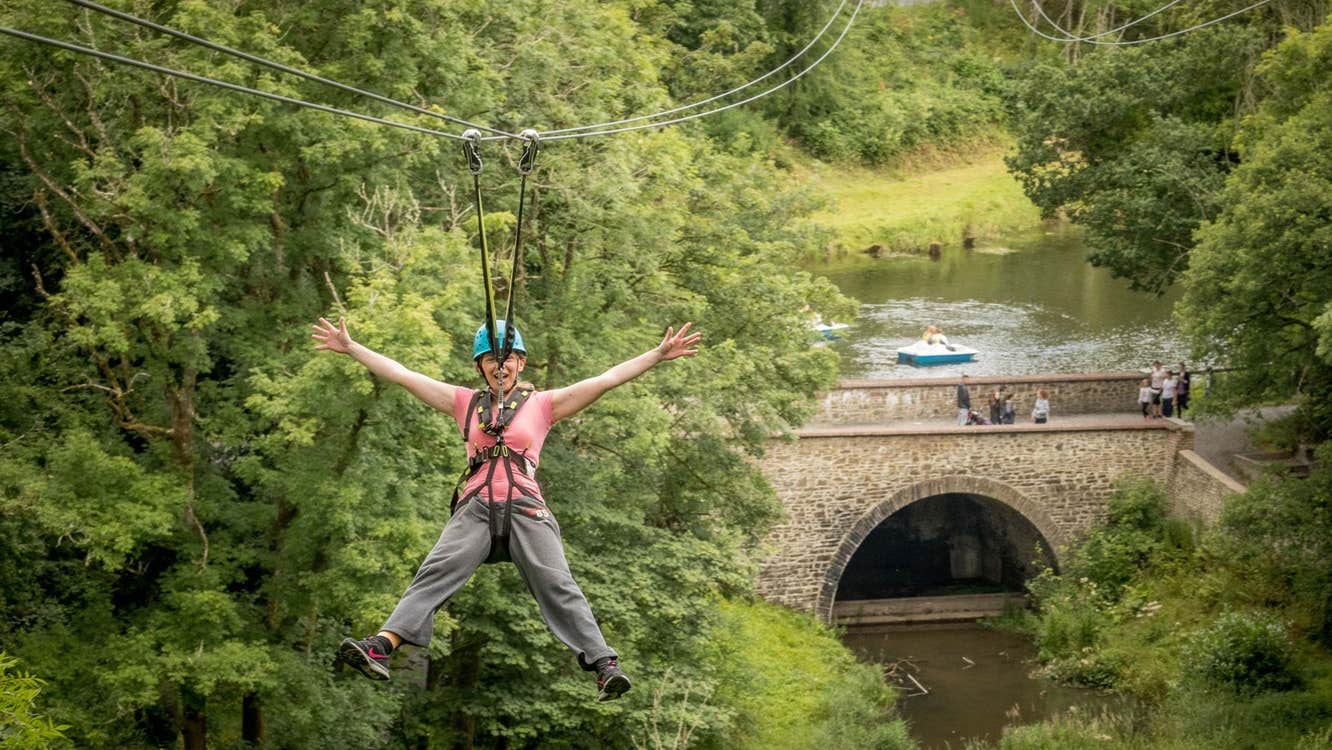 A person on a zipline wearing a harness and helmet