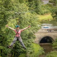 A person on a zipline wearing a harness and helmet