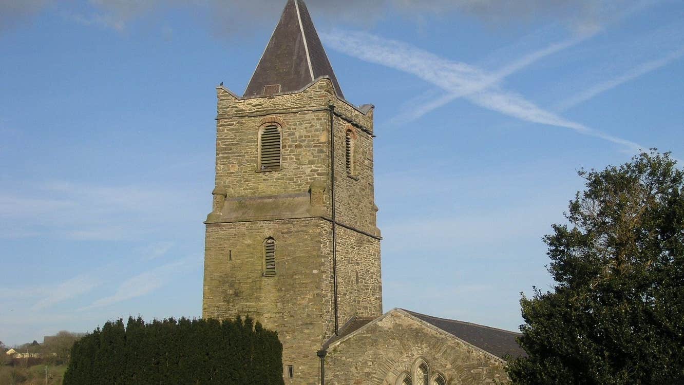 Church tower on a sunny day behind trees