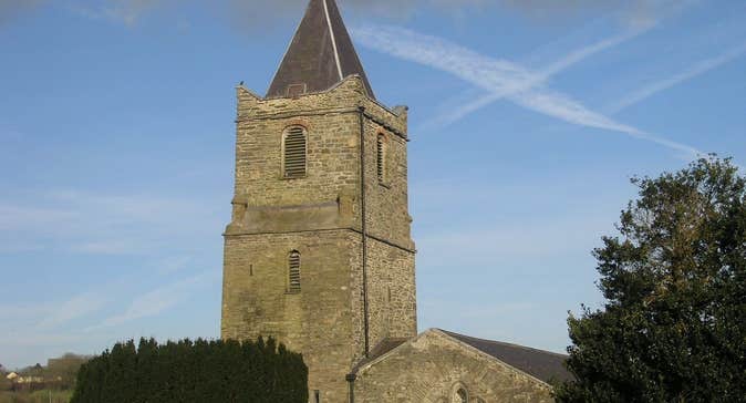 Church tower on a sunny day behind trees