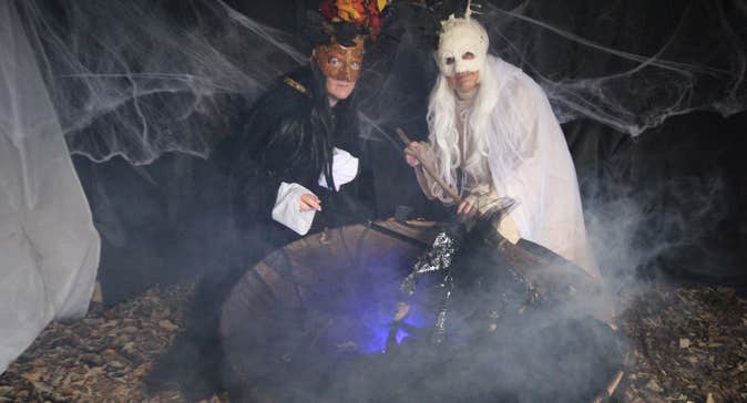 two people, one in white and one in black over a cauldron mixing it up