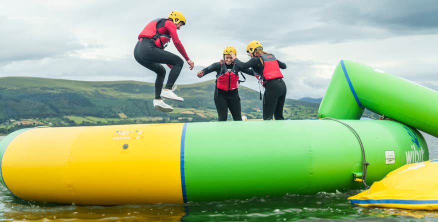Three people bouncing on a water trampoline at Carlingford Adventure Centre in County Louth.