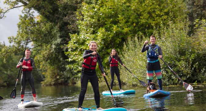 Four people and a dog enjoying paddleboarding in Killaloe Co. Clare