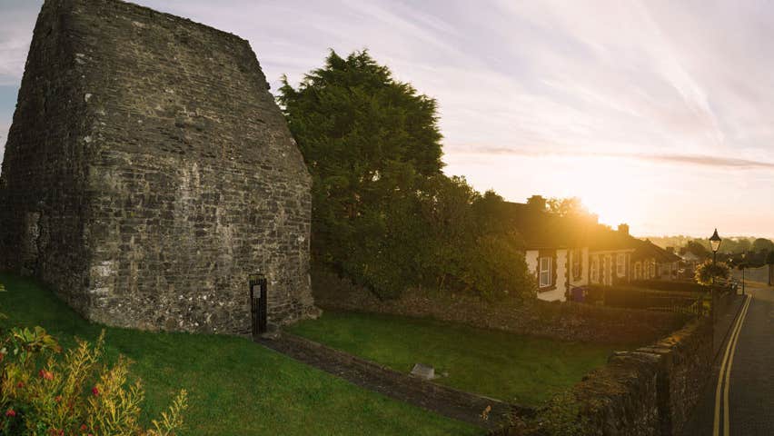 A small ancient stone building on a street lined with houses