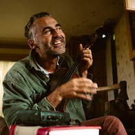 A smiling man seated in a chair with a tall lit candle
