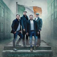 The High Kings - A group of 4 men outside on a couple of steps with old warehouse style buildings either side.