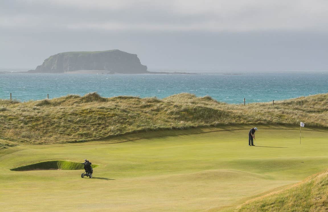 Golfer putting beside the sea at Rospaenna Golf Course, Donegal