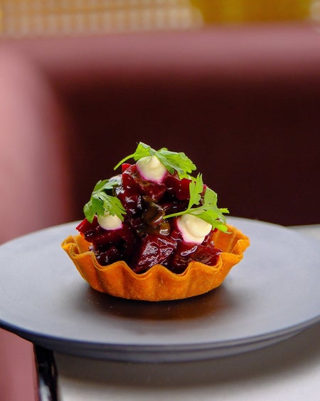 Small filled pastry on a grey plate on a table with red seating behind it