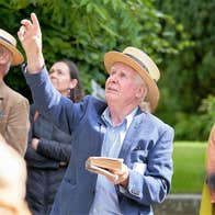 A small group of people looking upwards outdoors with central man pointing upwards.