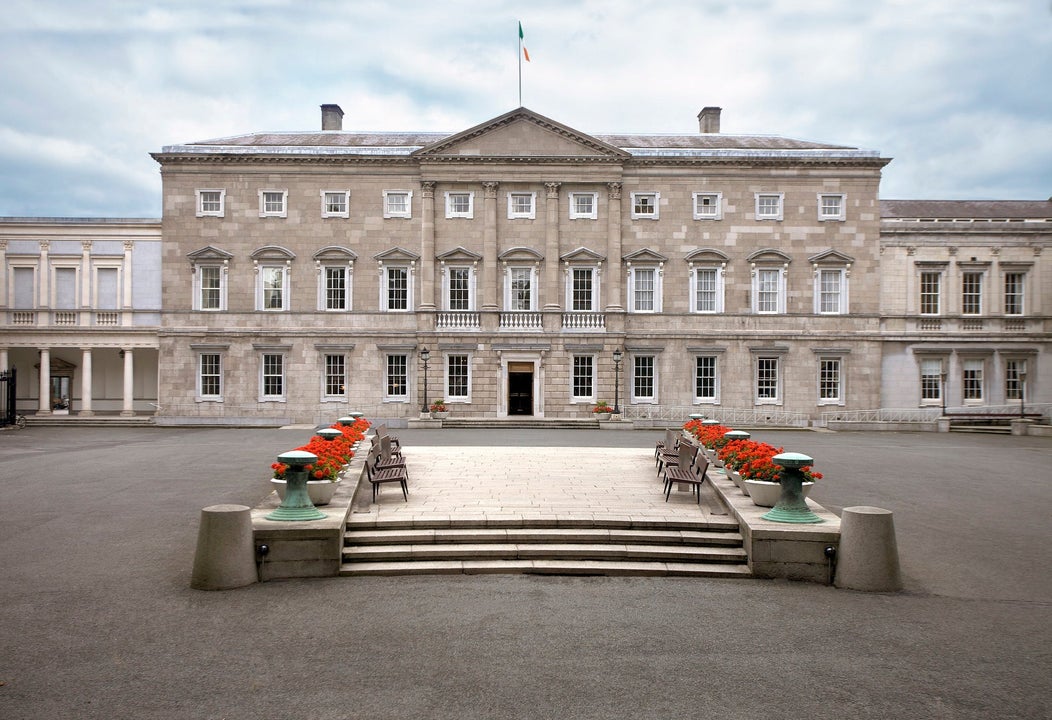 Exterior of a large Georgian mansion with steps lined with flowers in a large courtyard