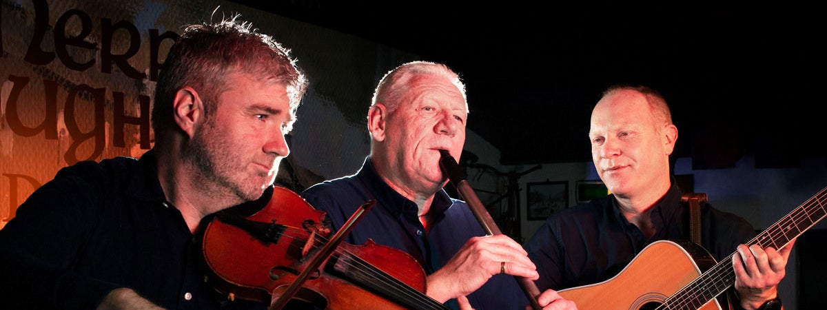 Three musicians playing instruments at the Merry Ploughboy Irish music pub in Dublin