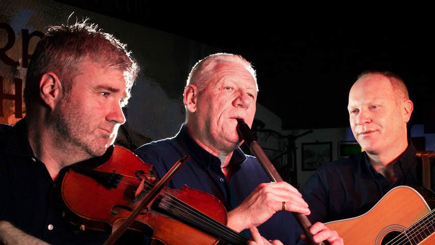 Three musicians playing instruments at the Merry Ploughboy Irish music pub in Dublin