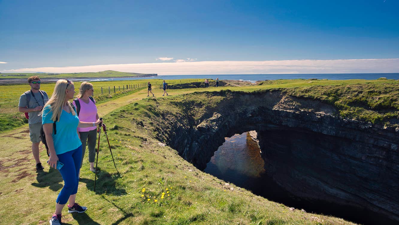 Three people admiring the Bridges of Ross in County Clare.