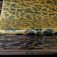 A long strip of patterned paper being rolled up from the print blocks