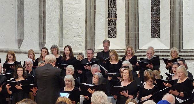 A photo of two choirs, Cór Mhaigh Eo and Louisburgh Voices, in Ballintubber Abbey, Mayo