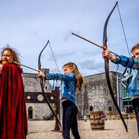 The castles resident archer with two girls all holding their bow and arrows in the courtyard