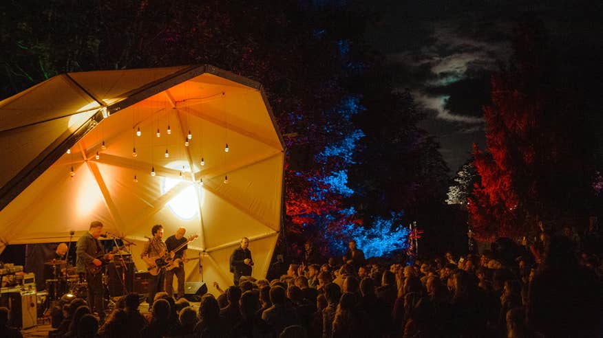 Audience surrounding a lit stage at an evening performance - Another Love Story festival.