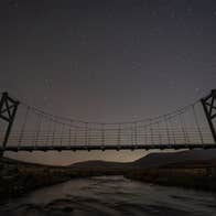 A darkened sky with stars behind a raised footbridge