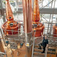 Clonakilty Distillery showing a guide in front of three copper stills