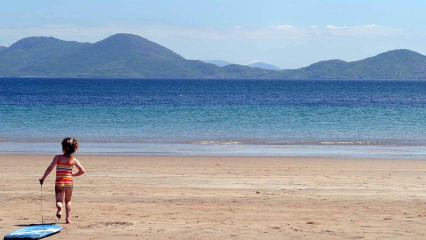 Child on Ballinskelligs Beach pulling surf board