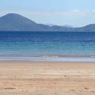 Child on Ballinskelligs Beach pulling surf board